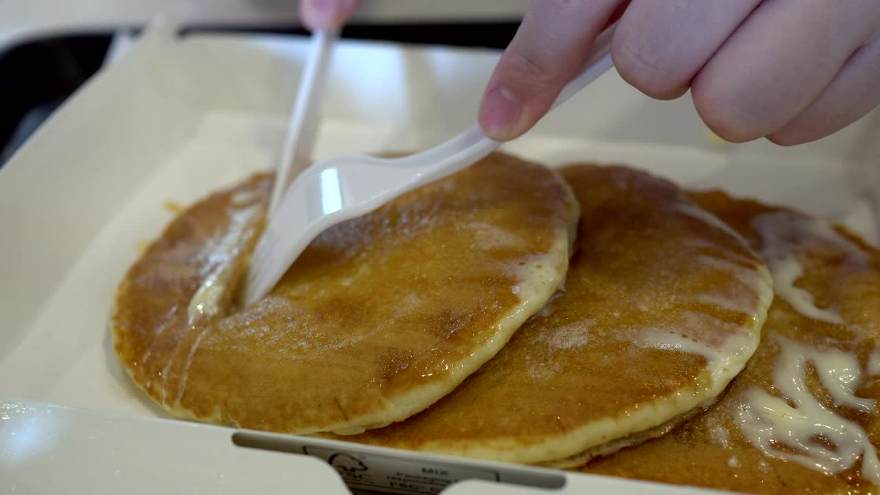 아이의 손에 칼과 포크를 고 아이가 팬케이크를 잘라내고 있습니다.