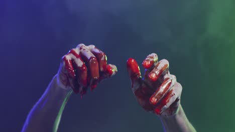 video of hands covered with blood moving over smoke on black background