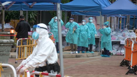 health workers and police officers wearing ppe suits are seen standing vigilant outside a building placed under lockdown after a large number of residents tested covid-19 coronavirus positive