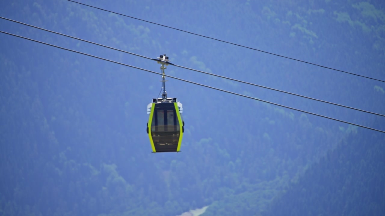 Funivia gialla che si muove attraverso una foresta montana.
