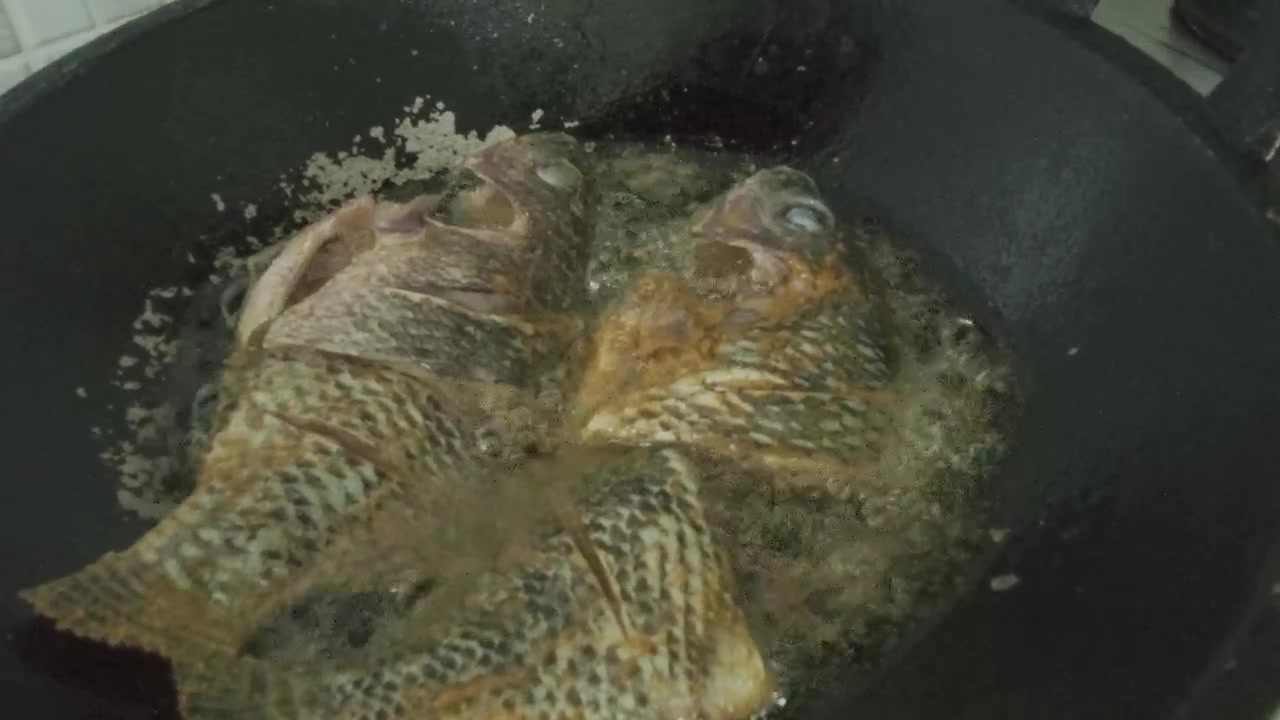 Pesce intero fritto in olio bollente in un wok