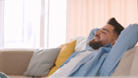 man relaxing peacefully on a couch at home