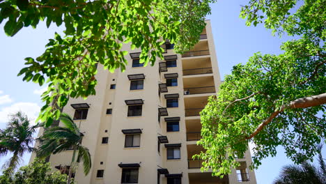 edificio de apartamentos retiro de la fachada bajo árboles tropicales con llamaradas de lente