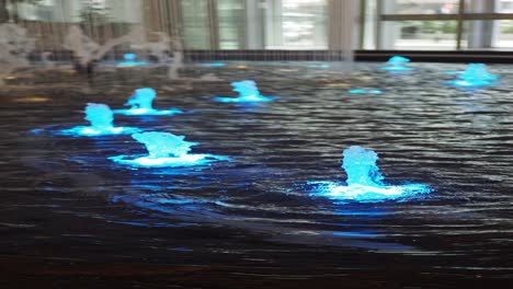 a modern indoor water fountain with purple and blue lights