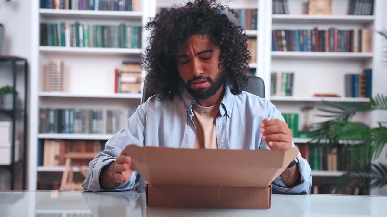 Distressed indian man discouraged by received parcel opens box and gets upset