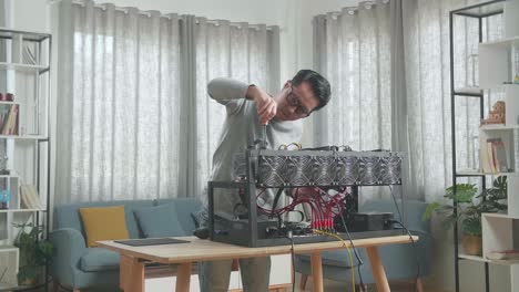 hombre asiático con gafas arreglando la plataforma de minería para la minería de criptomoneda