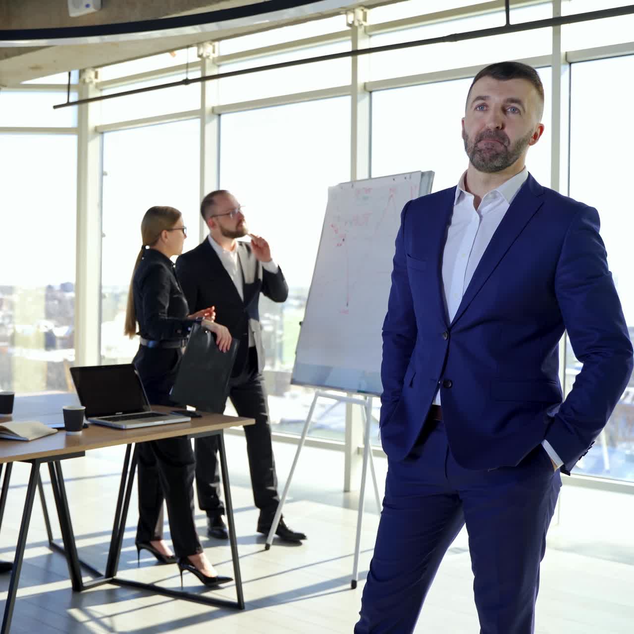 Male leader discussing work at office. Businessman in suit talking to business people colleagues or partners sitting at conference table