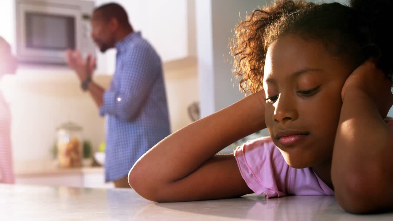 Fille triste écoutant ses parents se disputer dans la cuisine