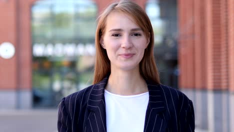 thumbs up by business woman at work looking at camera