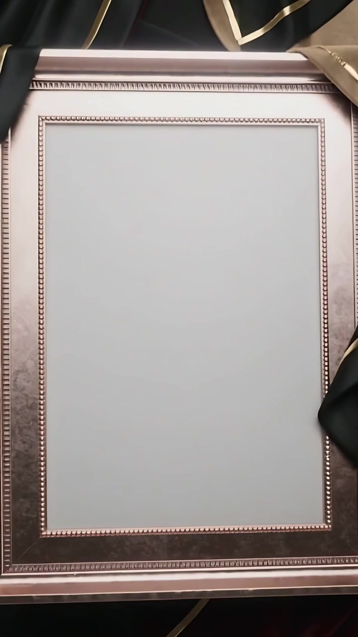 Vertical video: Shifting black satin gold-trim unveiling ornate frame at wall, showing blank panel