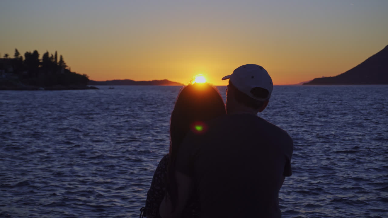 Silhouette Of Couple Watching Romantic Sunset Setting In The Ocean. - rear, closeup