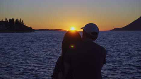 silhouette of couple watching romantic sunset setting in the ocean. - rear, closeup
