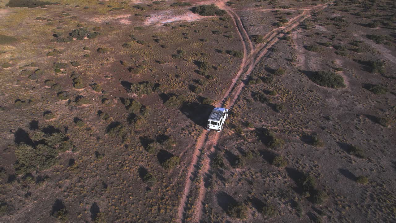 vista de dron inclinada hacia arriba revelando un coche conduciendo en el camino de tierra a través de las llanuras que conducen a la playa en bahia bustamante