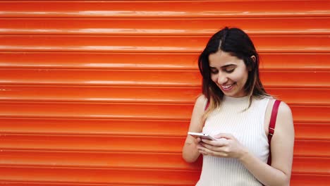 Slow-motion:Beautiful-young-girl-uses-smartphone-and-text-with-orange,red-background