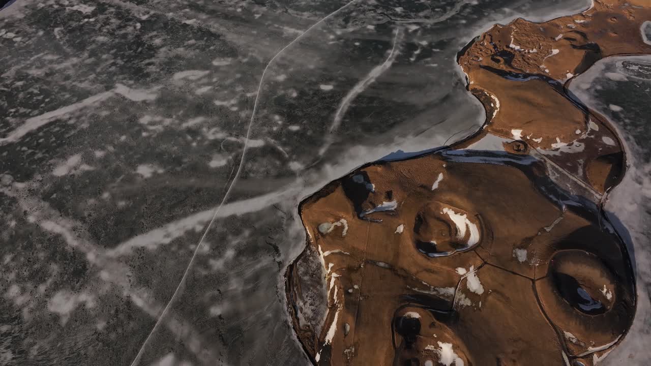 Stunning top-down drone view of Skútustaðir pseudo-craters beside icy Lake Mývatn in Iceland, winter terrain, unique volcanic forms and frozen beauty.
