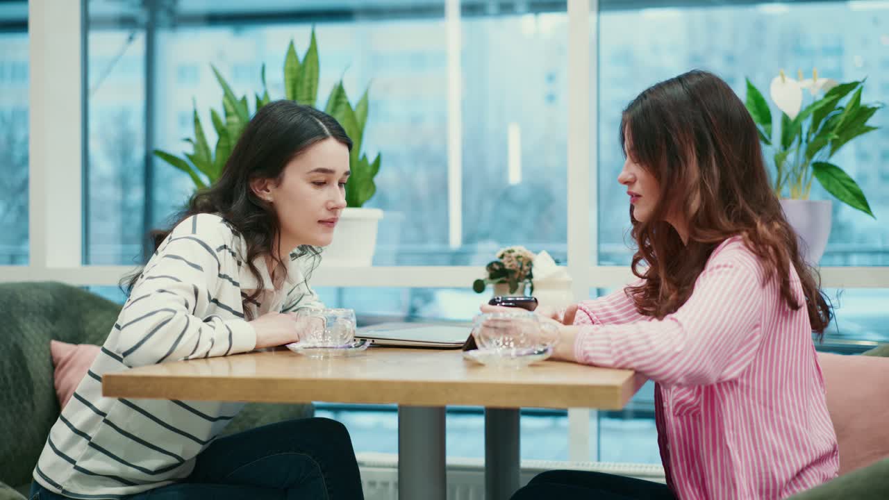 カフェで気軽に談笑する二人の若い女性。
