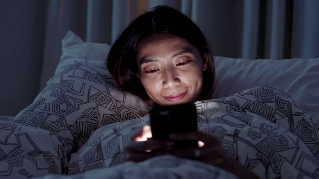 밤에 침대에서 드폰을 사용하는 여자