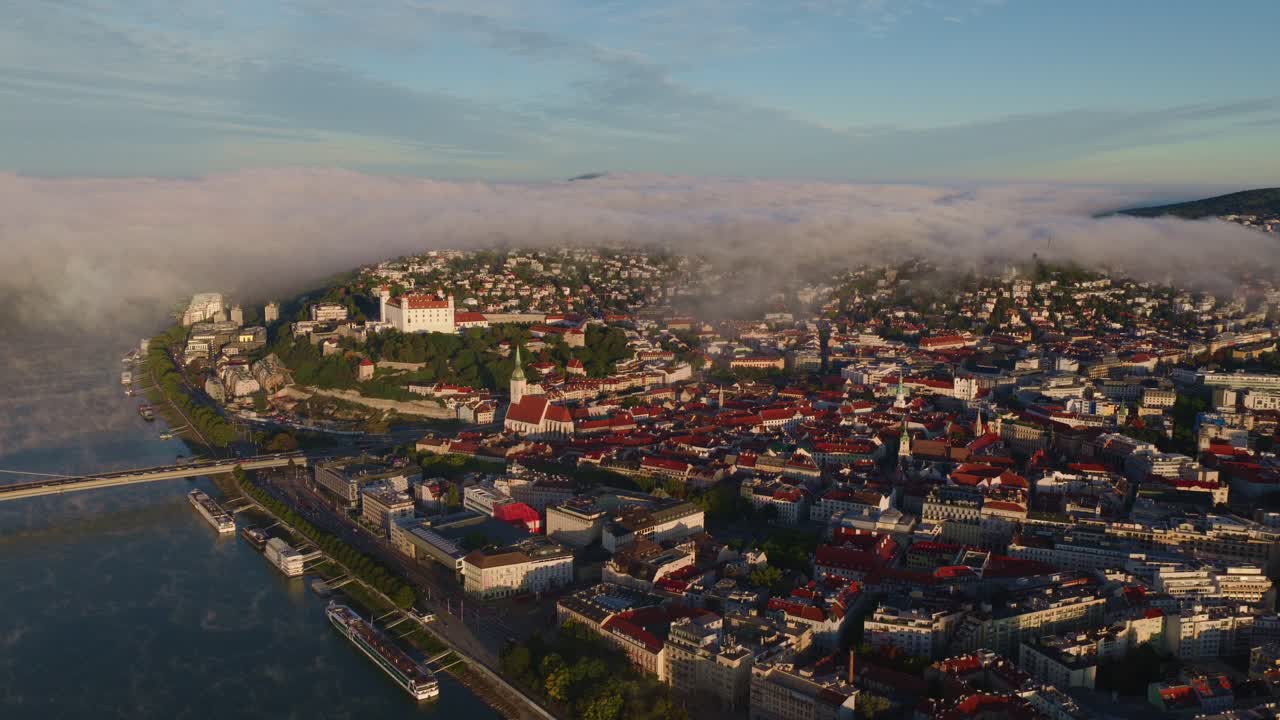 Aerial view of Bratislava, the capital of Slovakia, captured at sunrise with a blanket of morning mist rolling over the Danube River and the city’s historic core