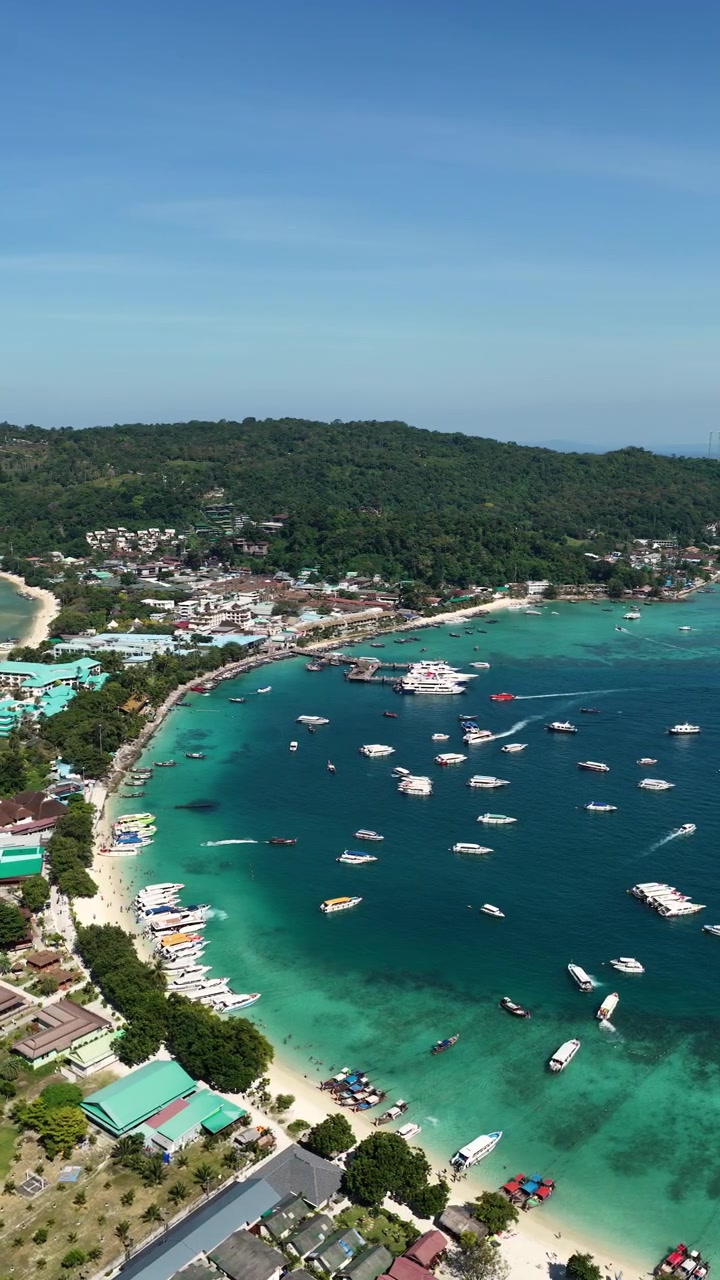 Ripresa aerea verticale sul porto di Phi Phi Don con barche in una baia turchese in Thailandia, con drone in orbita per stabilire la scena.