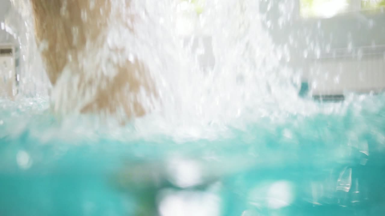 padre joven está levantando a su hijo pequeño del agua mientras le enseña a nadar en la piscina. niño feliz y su padre están riendo y divirtiéndose