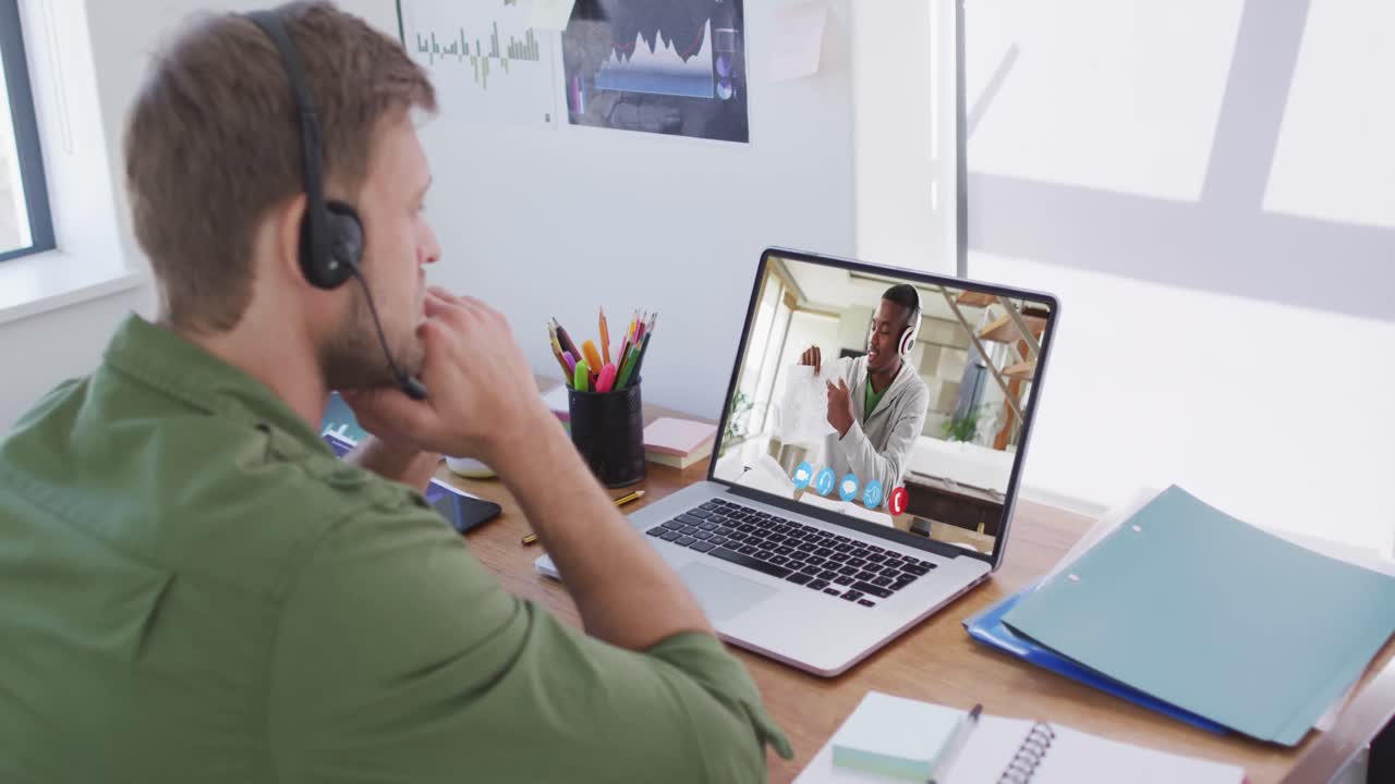 Kaukasisk forretningsmand sidder ved skrivebord og bruger laptop under videoopkald med mandlig kollega