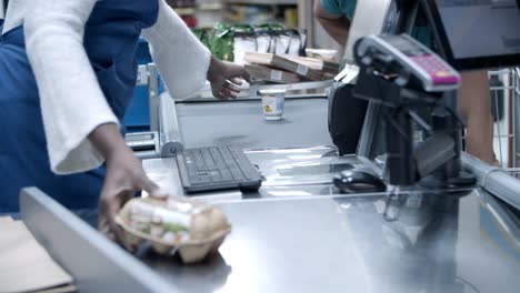 Side-view-of-cashier-scanning-goods-at-checkout