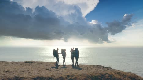 the four tourists are standing on the mountain top on seascape background