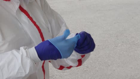 a medical worker in full ppe puts on a double layer of gloves at a coronavirus testing center during the covid-19 pandemic