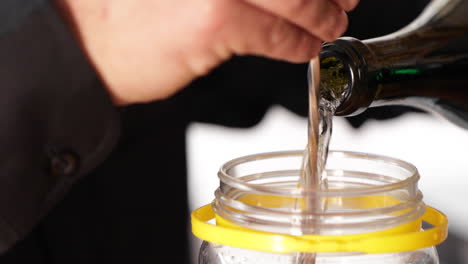 pouring white wine into a glass jar at the restaurant kitchen - close up