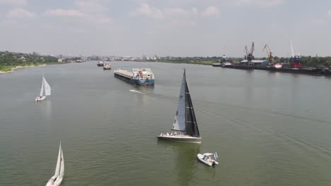 river scene with sailing boats and cargo ships