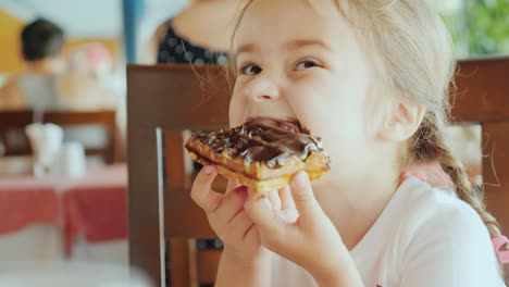 el pequeño amor estaba todo manchado con chocolate el niño está sentado en un restaurante y comiendo