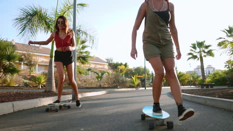 Con-Patinetas-En-Mano,-Recorren-Los-Senderos-Del-Parque-De-La-Isla-En-Cámara-Lenta,-Y-El-Brillo-Del-Atardecer-Mejora-Su-Experiencia.-Alegría-Y-Un-Estilo-De-Vida-Saludable