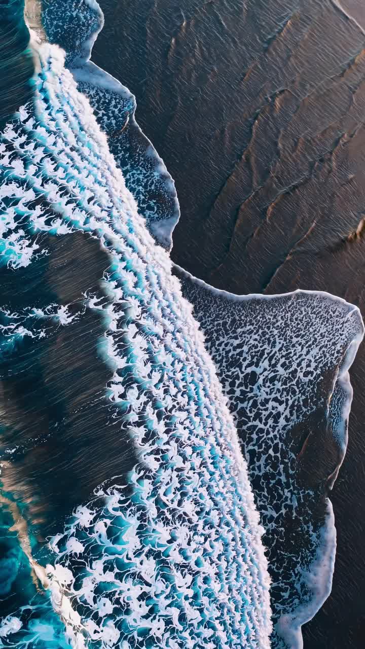 Vista aerea di onde oceaniche che si infrangono sulla riva, catturando il movimento dinamico per un video sereno.