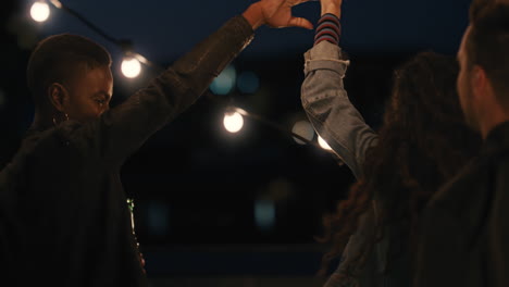 happy multiracial friends having fun dancing playfully together enjoying rooftop party at night laughing celebrating friendship