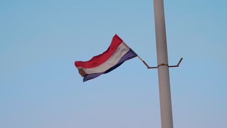 slowmotion footage of flag blowing in the wind with red, white and blue colors on a gray pole