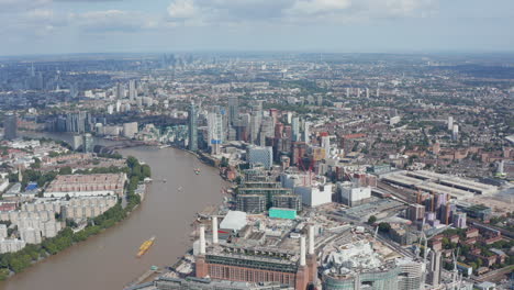 Aerial-view-of-large-city.-Tall-office-and-apartment-buildings-of-Thames-river-south-bank.-Historic-building-of-former-coal-power-plant.-London,-UK
