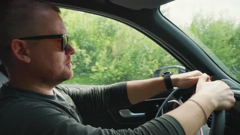 man driving a car through a forest