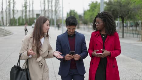 Caucasian-and-Afro-american-women-talking,-man-texting-on-phone