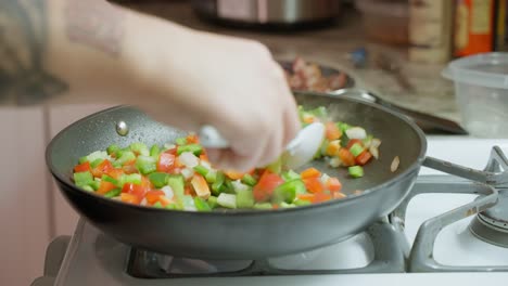 Frying red and green peppers and onions in a Teflon frying pan over low heat