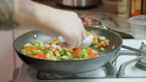 freír pimientos rojos y verdes y cebollas en una sartén de teflón a fuego lento