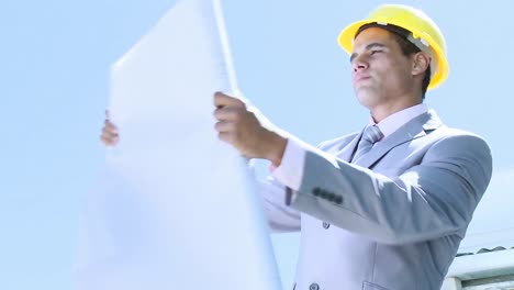 engineer working outdoors with plans and a hard hat on