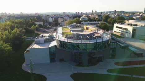 Toma-Aérea-De-Un-Campus-Moderno-Con-Una-Pista-Para-Correr-En-El-Techo-De-Un-Edificio-Moderno