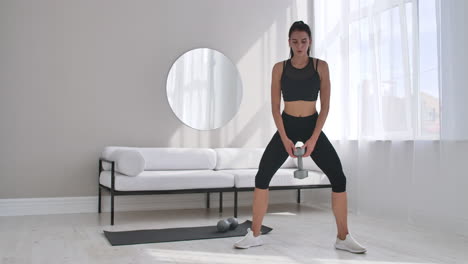 young fitness woman doing squat with dumbbells in hands.