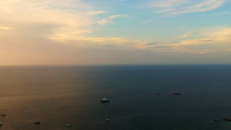 Aerial-shot-of-an-Ocean-with-a-speed-boat,-long-tail-boat-next-to-it-and-a-cloudy-blue-sky-in-the-background