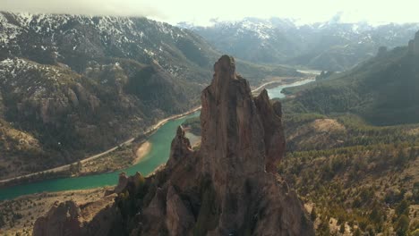 Toma-Aérea-Orbitando-Una-Impresionante-Formación-Rocosa-Con-Un-Valle-Fluvial-Al-Fondo-En-La-Región-De-La-Patagonia,-Argentina.