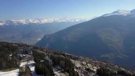 Stunning-aerial-view-of-ski-village-and-mountain-range-in-Swiss-Alps