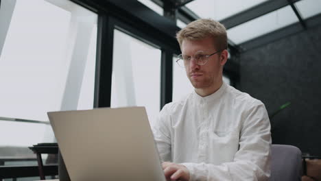 serious busy businessman is working with laptop in his modern office typing email and sending message