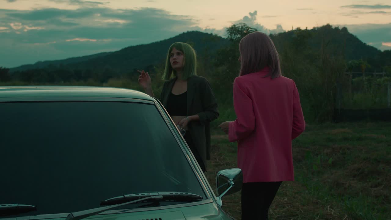 Two Women by a Vintage Car at Sunset