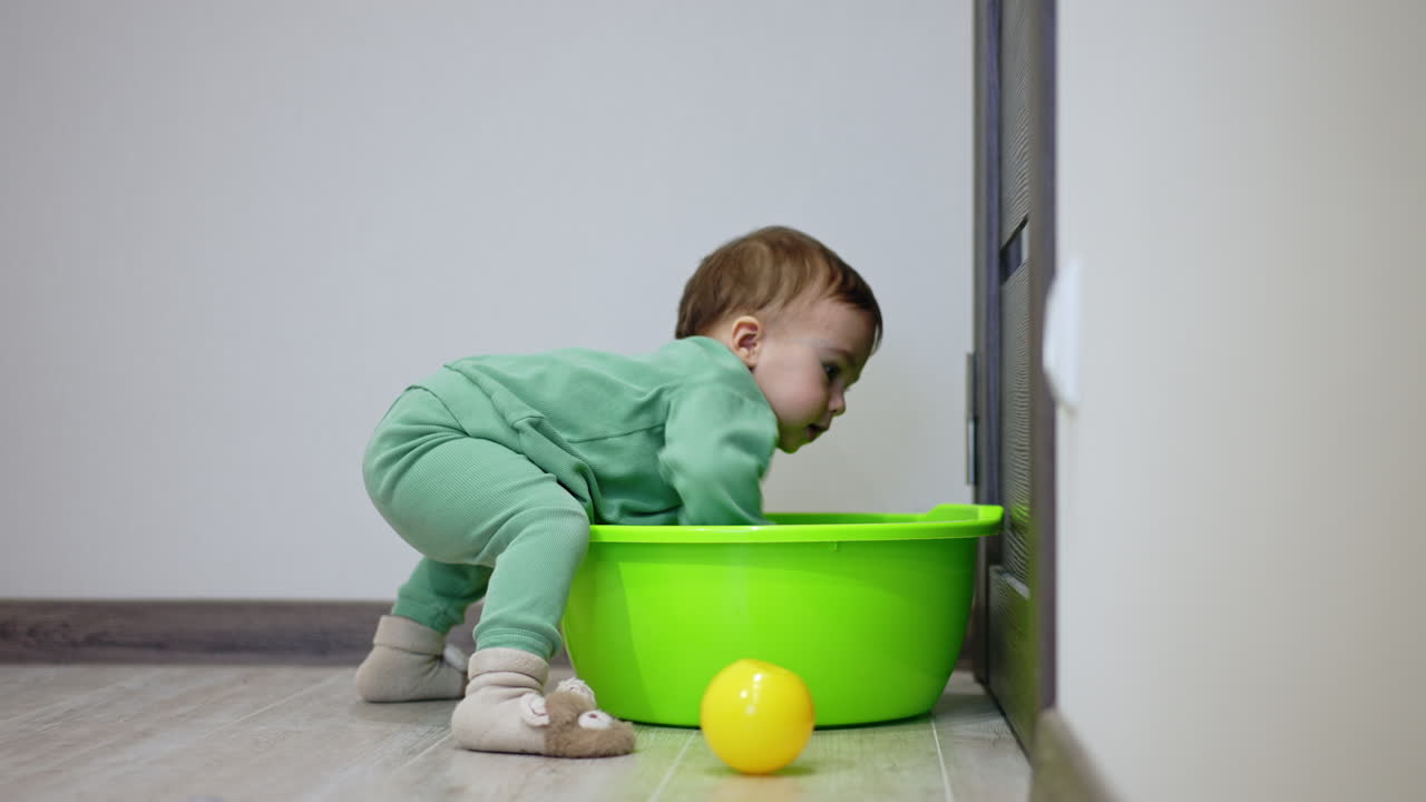 Baby Playing with a Green Basin and Ball