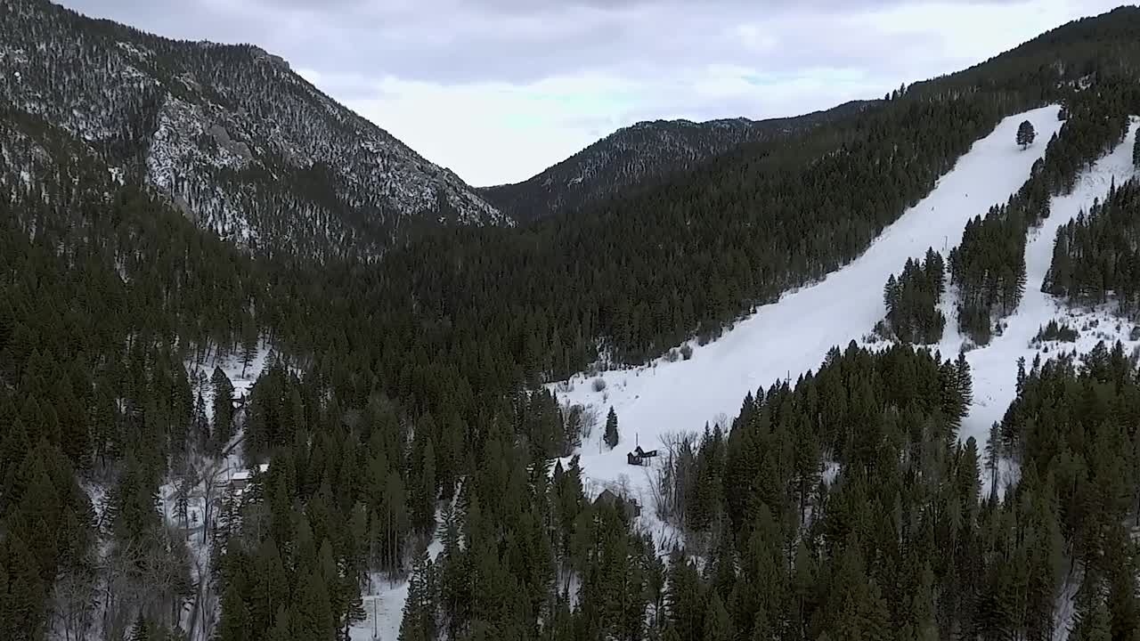 AEREA - La telecamera si allontana da un profondo canyon di montagna coperto di alberi e neve